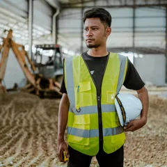 Homme en gilet de sécurité tenant un casque — photo d’illustration