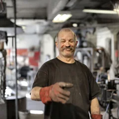 Artisan aux cheveux gris souriant dans un atelier — photo d’illustration