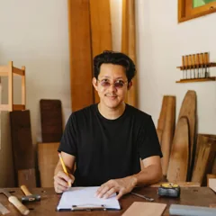 Homme avec lunettes assis à un établi dans un atelier — photo d’illustration